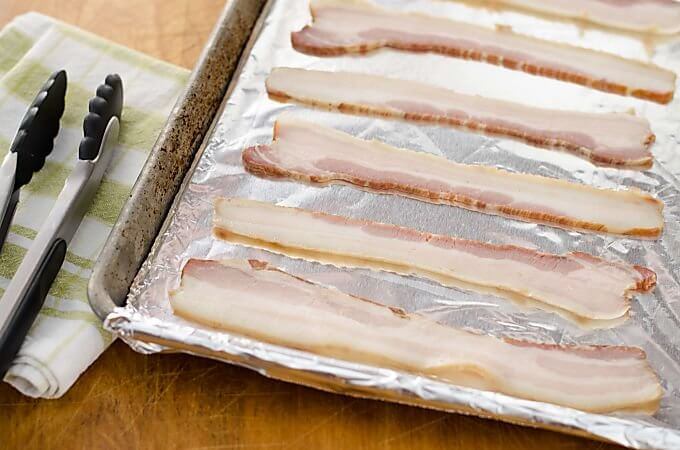 Bacon on baking sheet ready to be cooked in the oven.