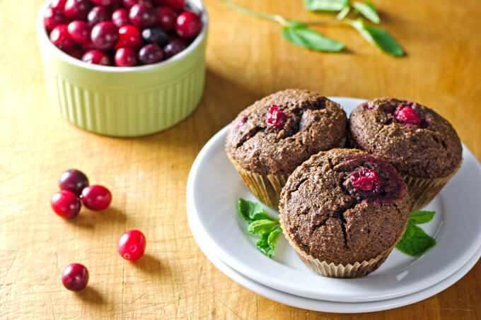 chocolate cranberry muffins on plate with bowl of cranberries