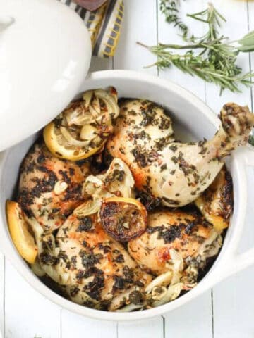 Lemon herb roasted chicken and fennel in white baking dish.