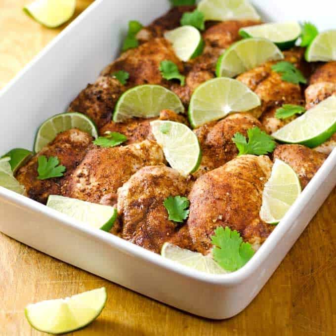 Baked chicken thighs garnished with limes and cilantro