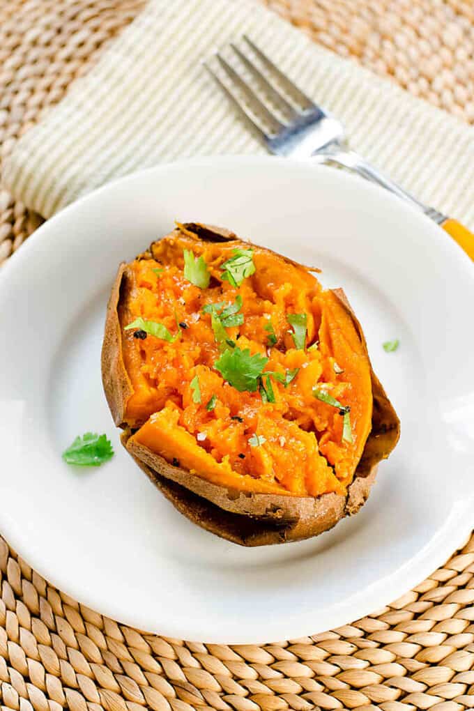 Slow cooked sweet potato on plate, garnished with cilantro and sea salt