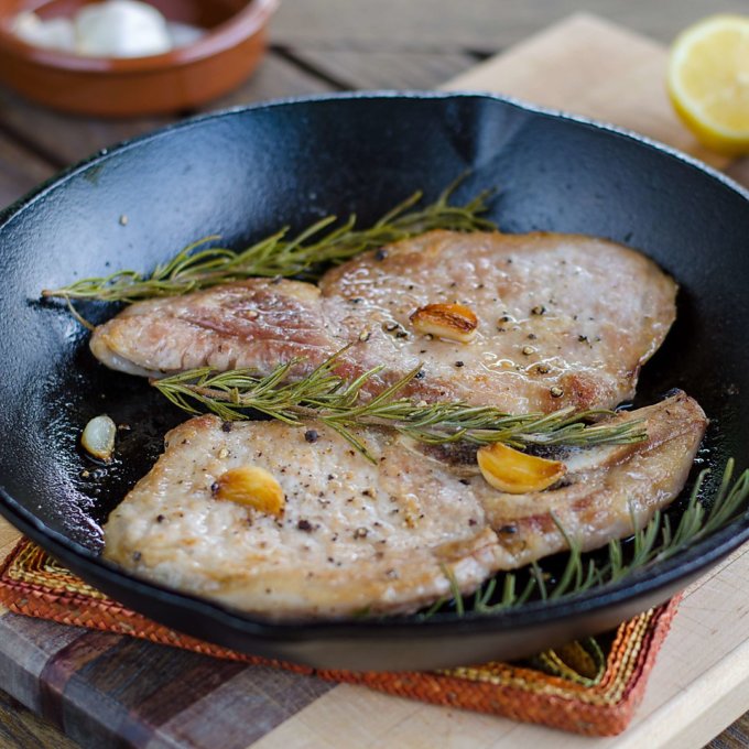 Pork chops with garlic and rosemary in cast iron pan