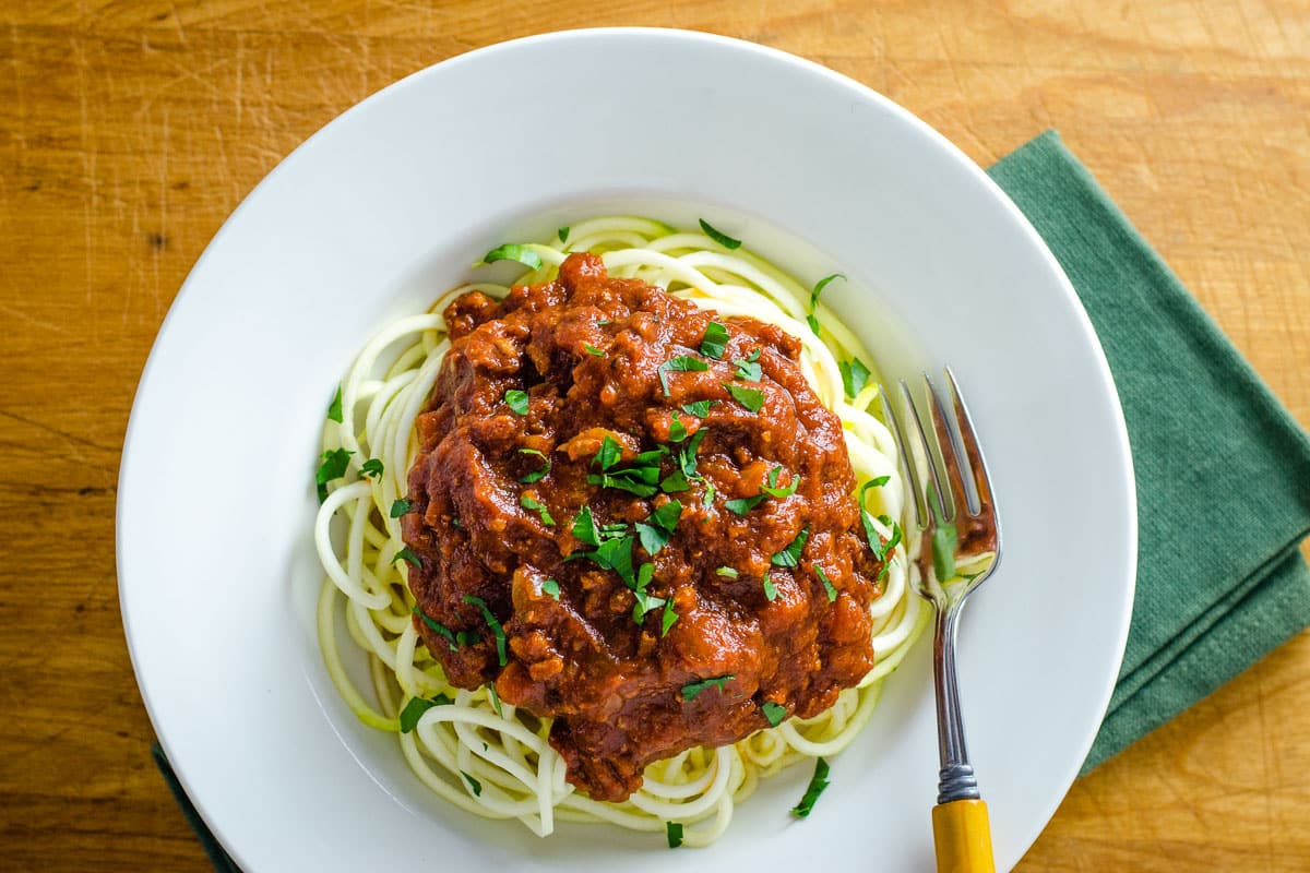 Slow cooker turkey Bolognese with zucchini noodles in white bowl with fork.