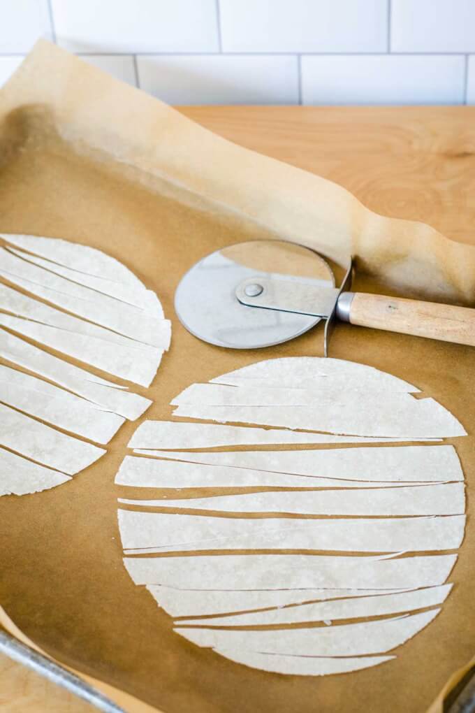 Cassava flour tortillas cut into strips with a pizza cutter on a baking sheet lined with parchment paper.