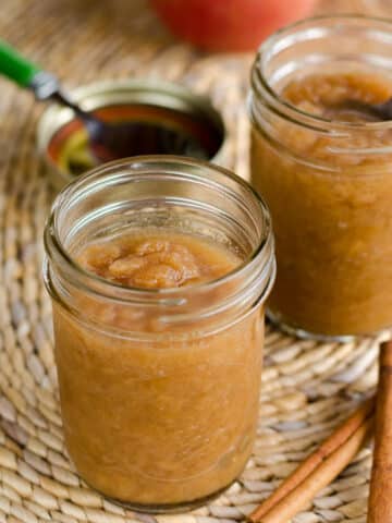 Crockpot applesauce in small mason jars with cinnamon sticks.