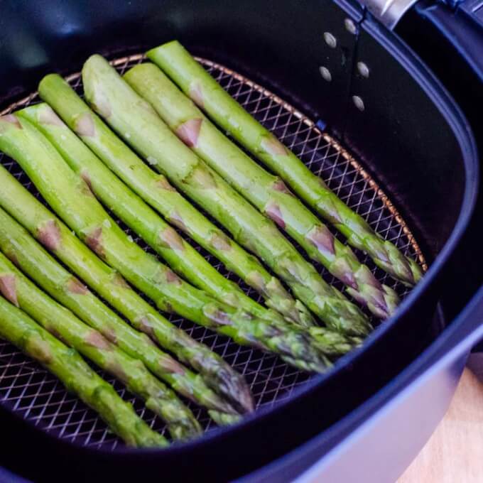 Raw asparagus in air fryer basket