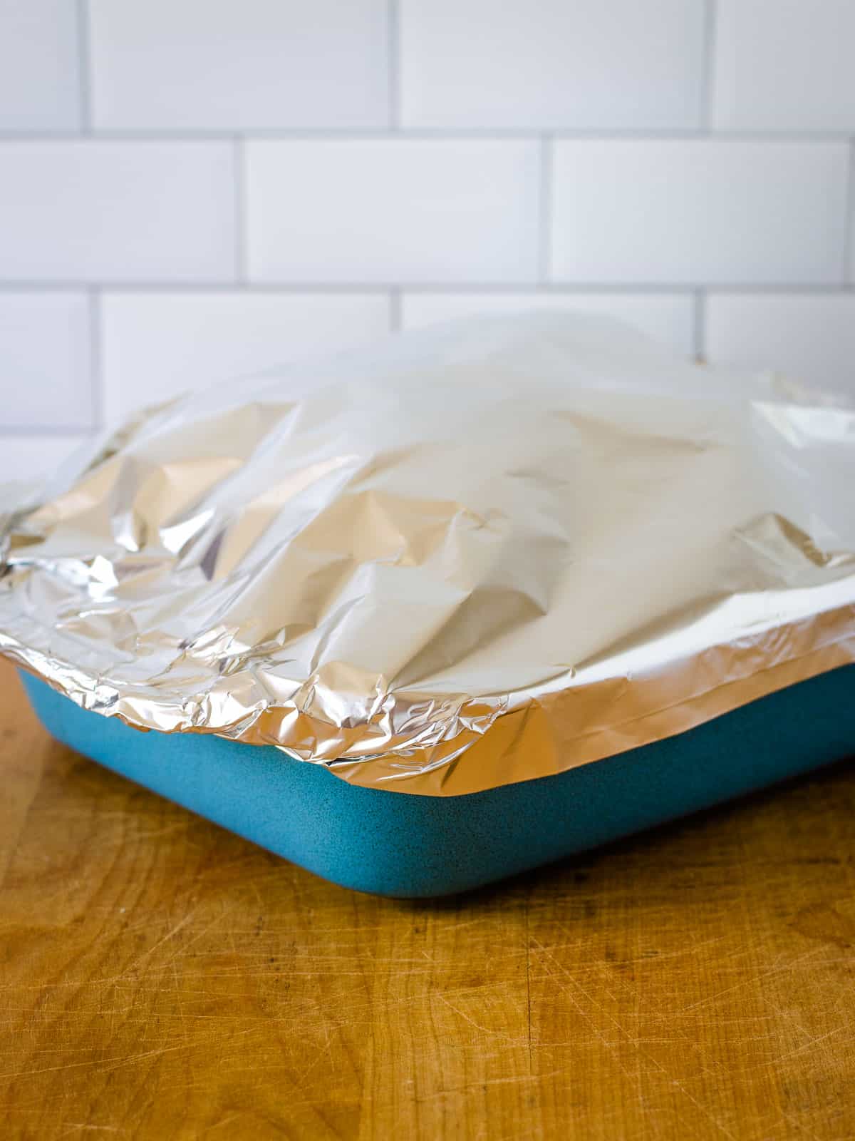 Chicken in baking dish covered in aluminum foil