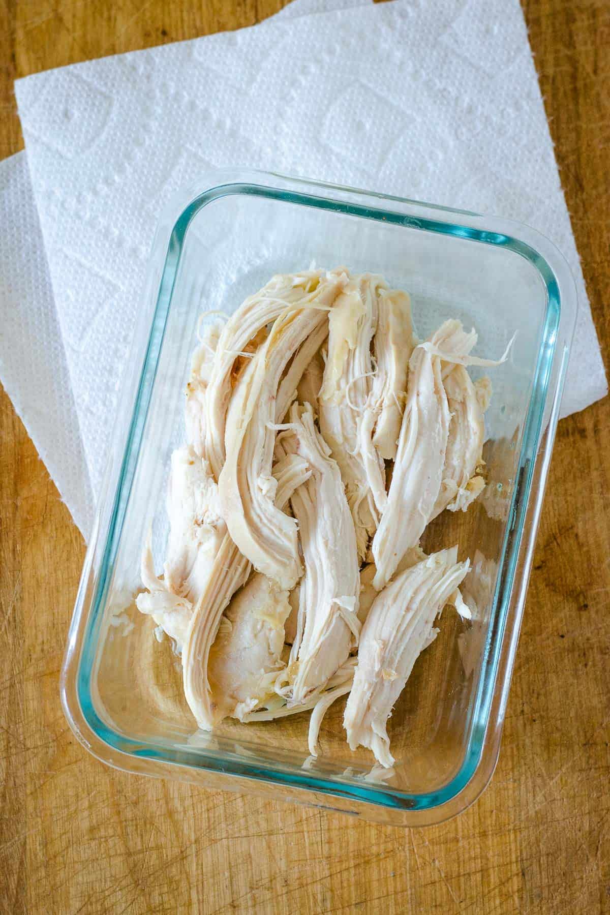 Shredded chicken in glass dish with paper towel