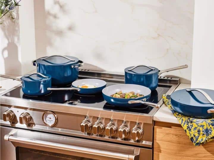 Blue pots and pans on stove top including small pan with fried egg and large frypan with vegetables.