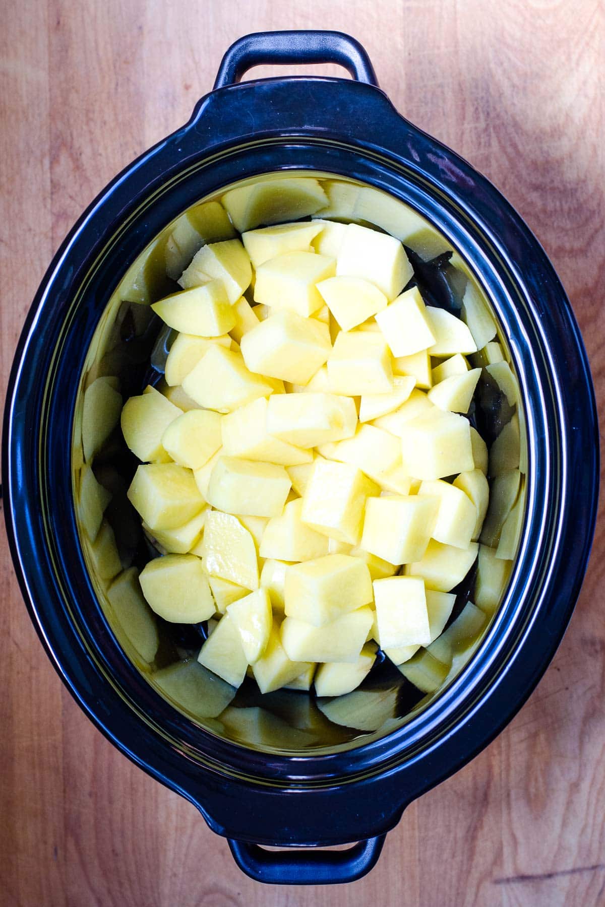 Cut up potatoes in crock pot.