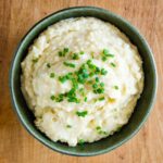 Slow cooker mashed potatoes garnished with chives.