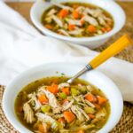 Two bowls of turkey soup with spoons.