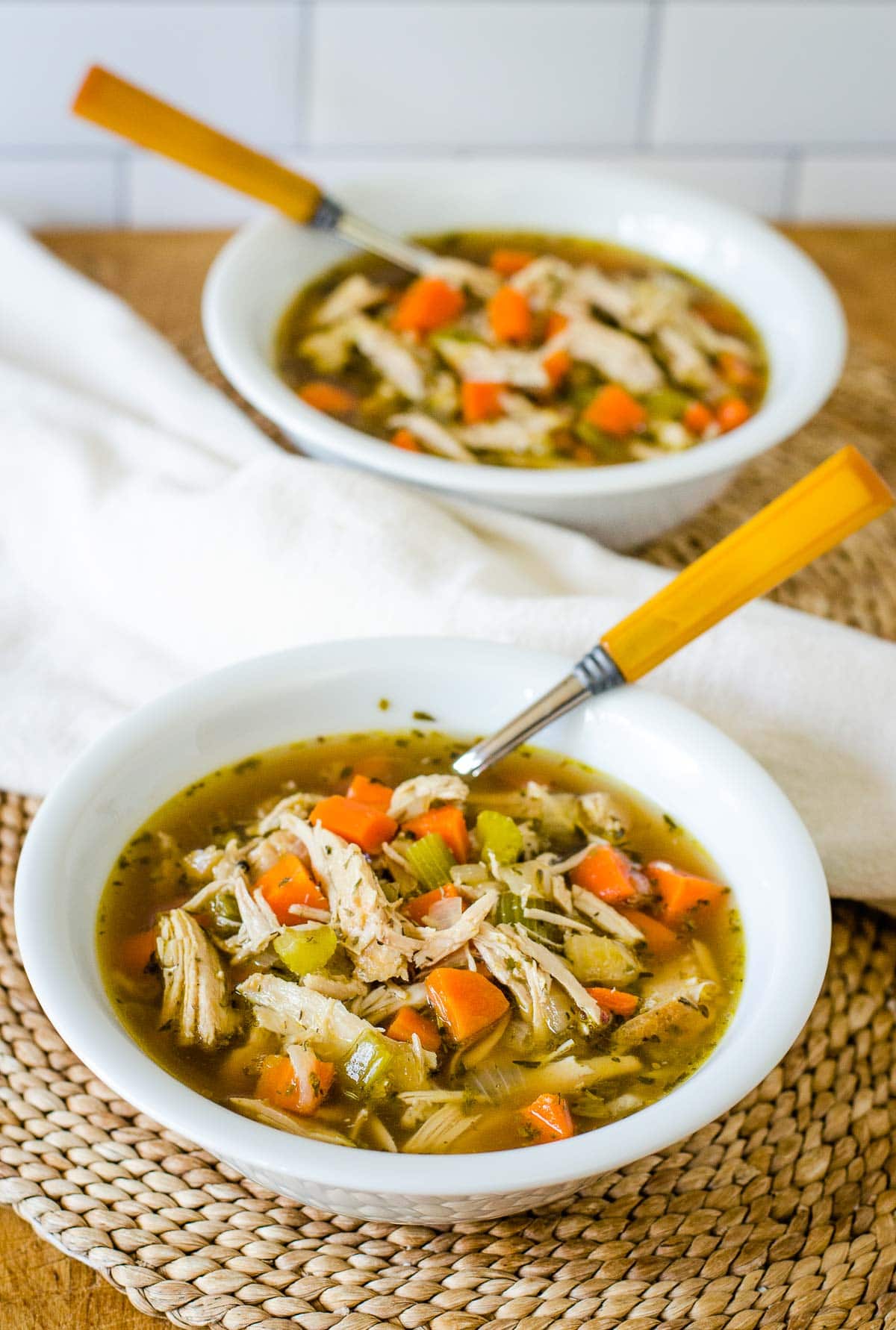 Two bowls of turkey soup with spoons.
