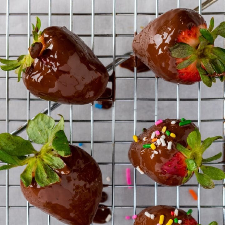 Chocolate dipped strawberries on wire rack, some with sprinkles.