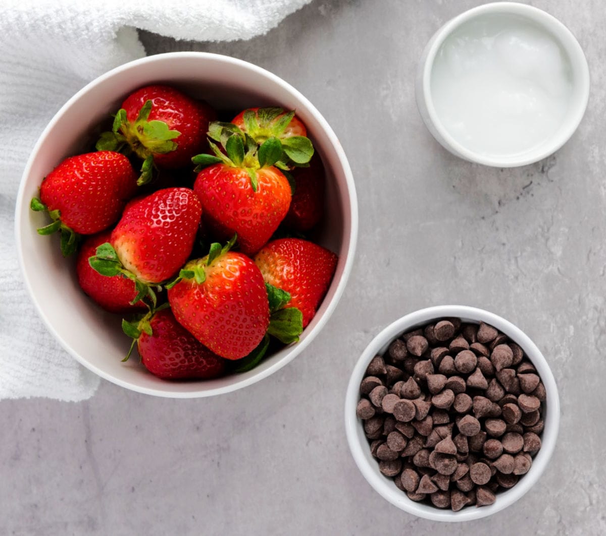 Bowls of strawberries, chocolate chips and coconut oil.