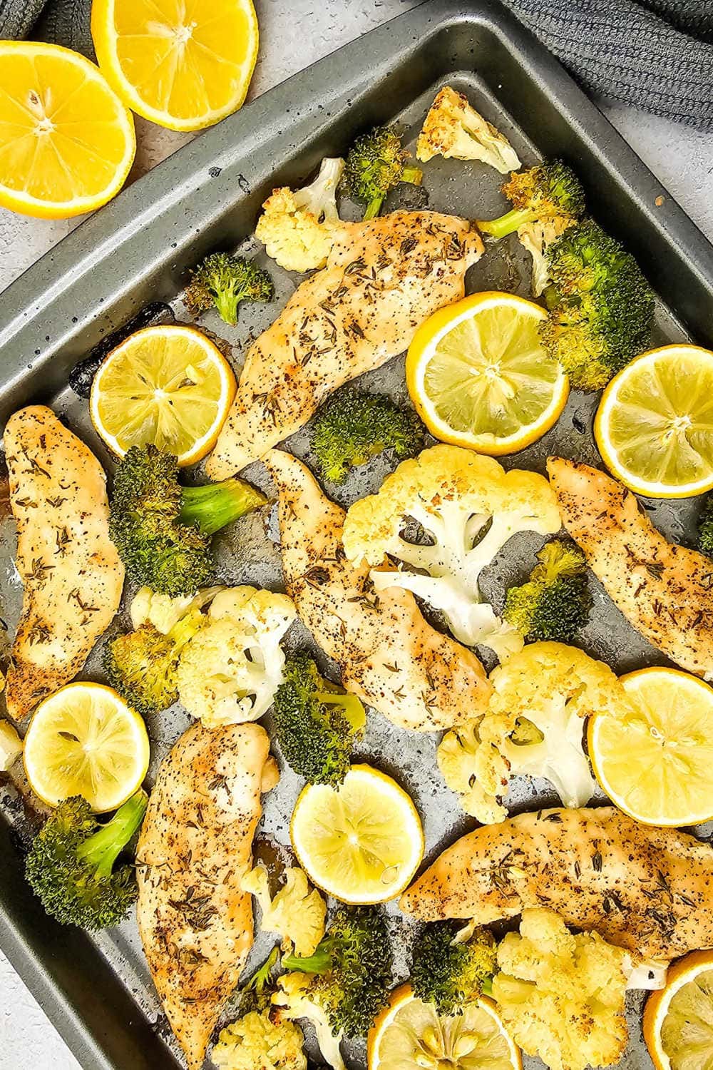 Oven baked sheet pan chicken and veggies with broccoli, cauliflower and lemon..