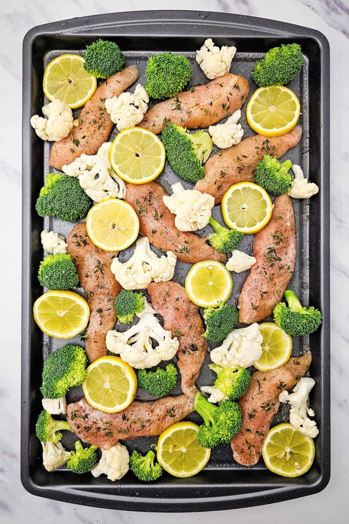 Sheet pan of chicken and vegetables for baking.