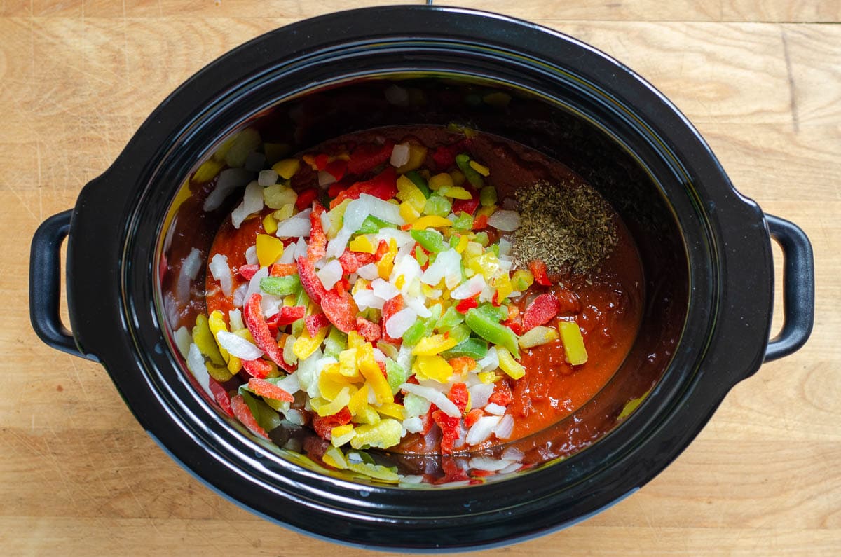 Tomato sauce, herbs, frozen peppers and onions in crock pot.