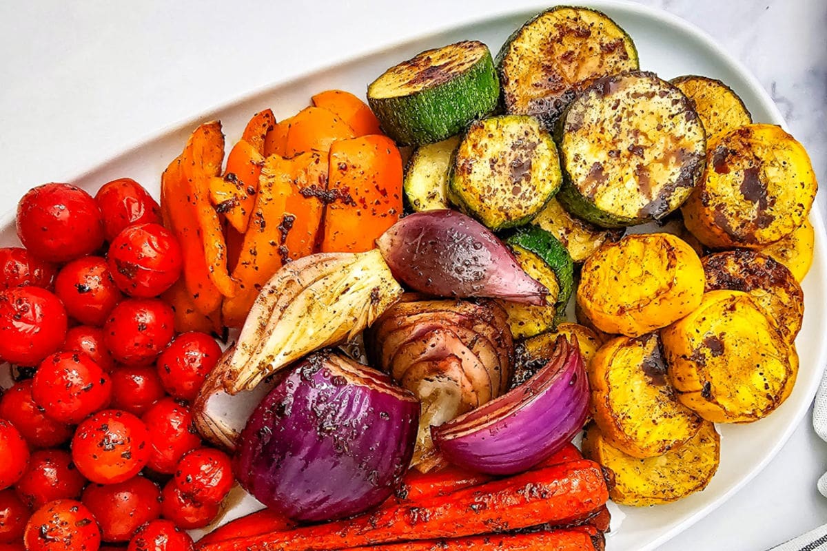 Grilled marinated vegetables on a white platter.