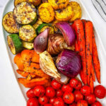 Grilled marinated vegetables on a white platter.