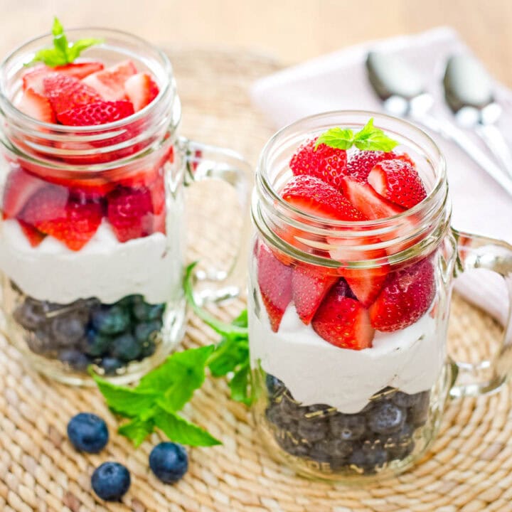 Red, white and blue berries and cream in glass mason jar mugs.