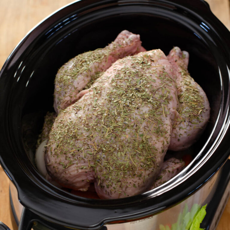 Whole chicken in a crockpot ready to cook.
