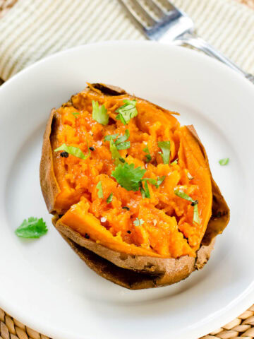 Slow cooker "baked" sweet potato half on white plate garnished with cilantro.