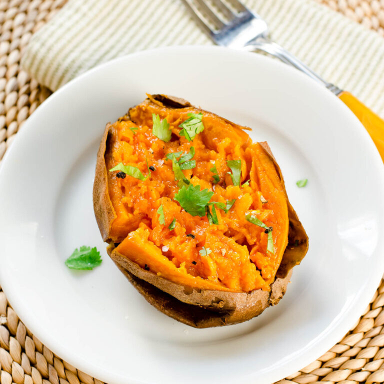 Slow cooker "baked" sweet potato half on white plate garnished with cilantro.
