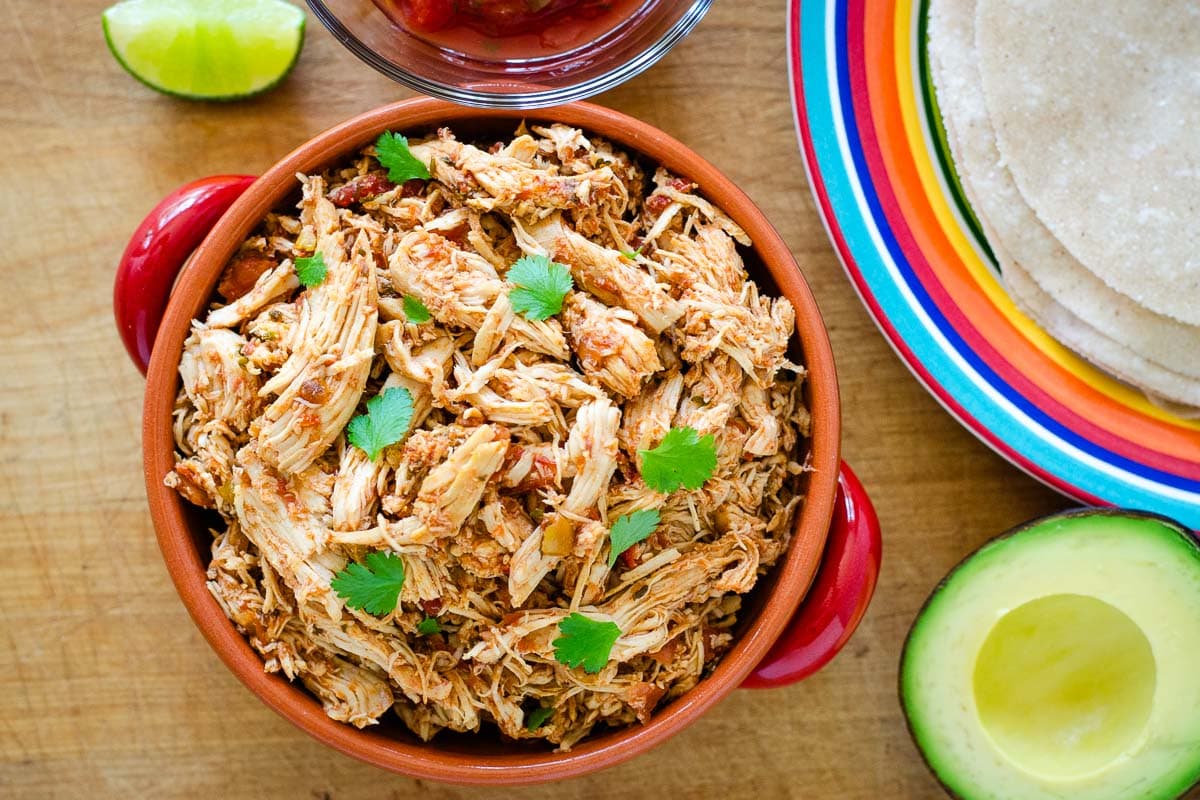 Crockpot salsa chicken with tortillas, avocado and lime for tacos.