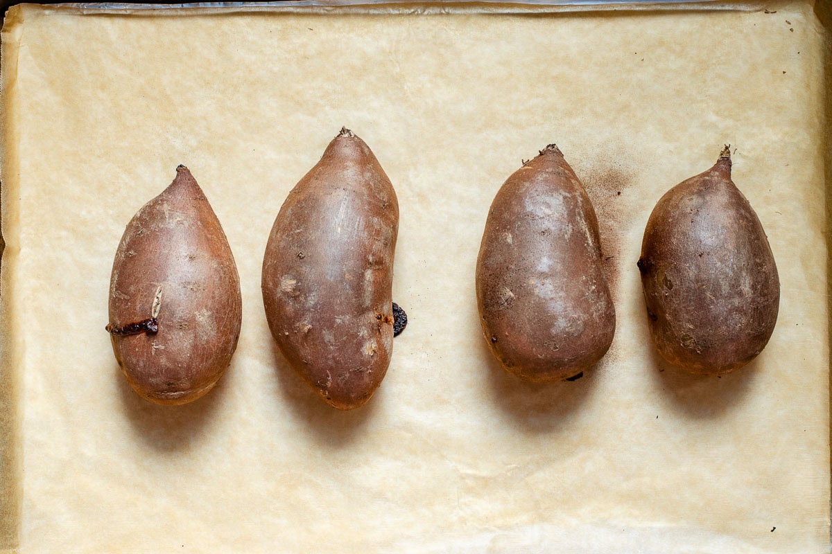 Roasted sweet potatoes on a baking sheet lined with parchment paper.